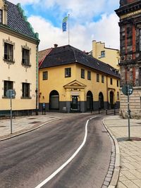 Road by buildings against sky in city