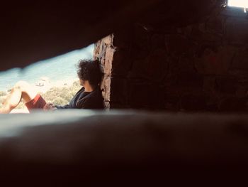 Side view of a boy sitting against wall