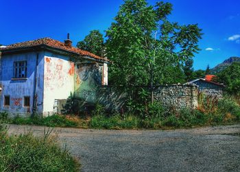 Old building by road against blue sky