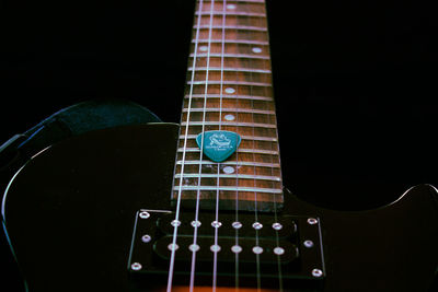 Close-up of guitar on table against black background