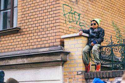 Full length portrait of young man against wall in city