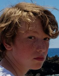 Close-up portrait of teenage boy at beach