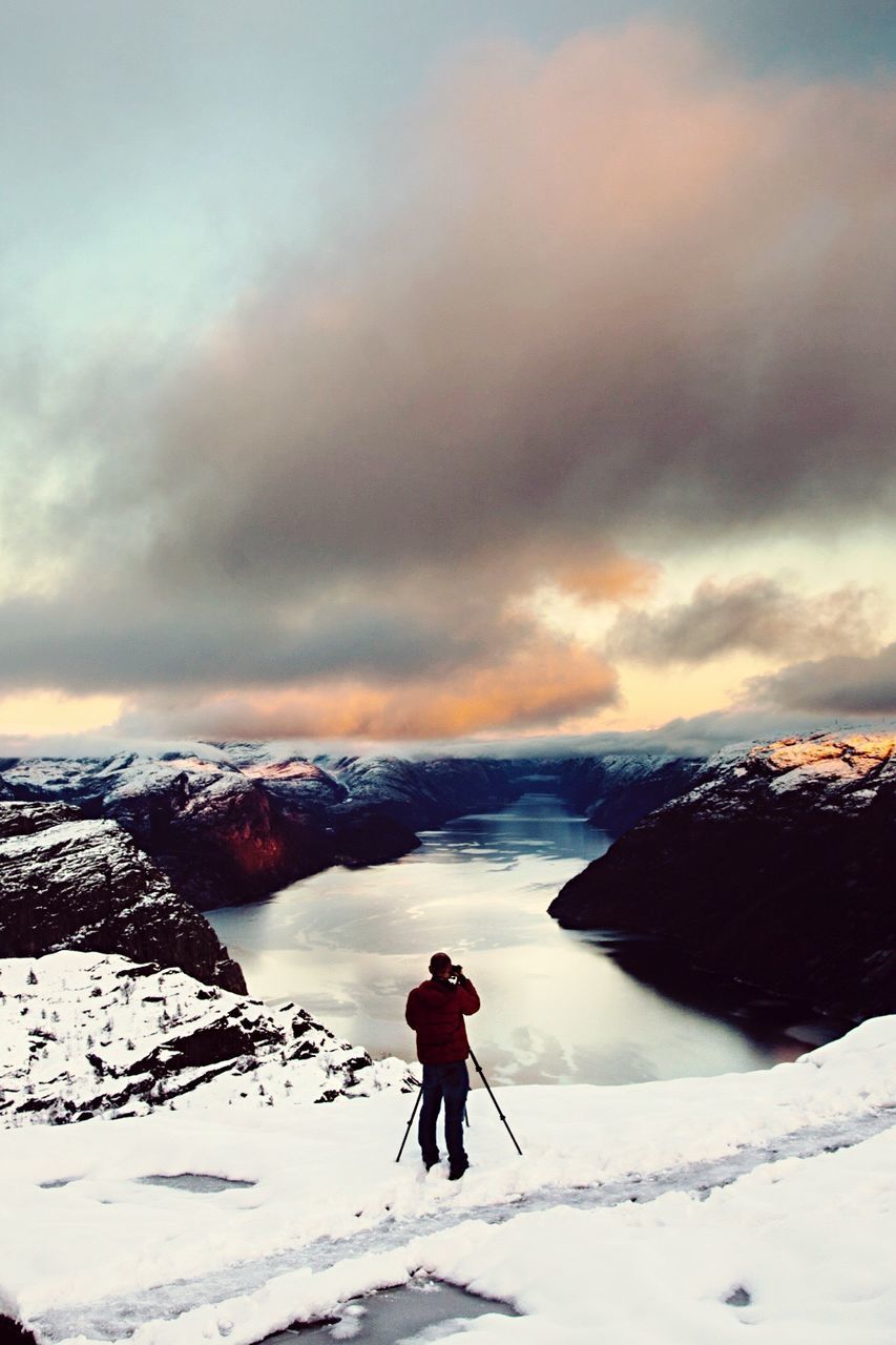 MAN STANDING ON SNOWCAPPED MOUNTAINS AGAINST SKY