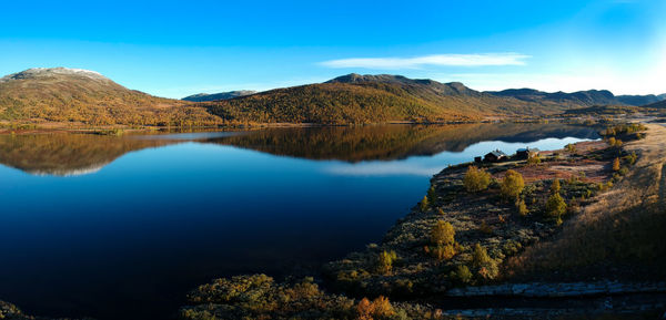 Scenic view of lake and mountains against blue sky