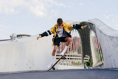 Caucasian teenager jumping with a skateboard in the middle of the bridge in the city