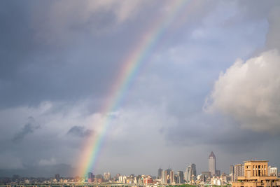 Rainbow over city against sky