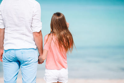 Rear view of couple standing at beach against sky