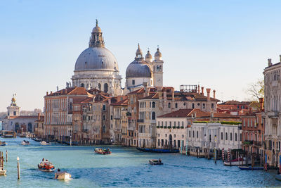 Boats in canal amidst buildings against sky