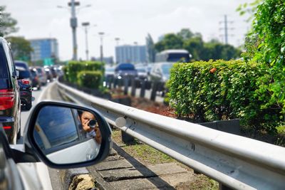 Reflection of man in car mirror on road