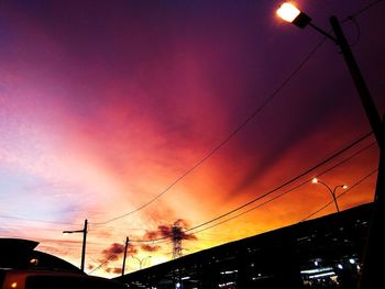 Low angle view of silhouette electricity pylon against sky at sunset