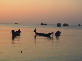 Silhouette people on sea against sky during sunset