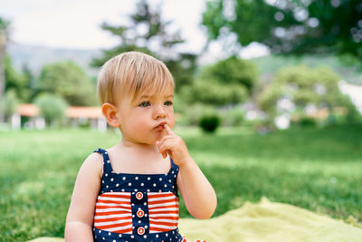 Cute girl looking away while sitting at lawn