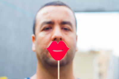 Close-up portrait of mid adult man holding lips prop