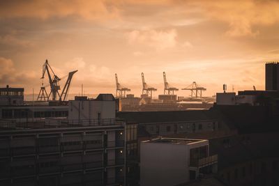 Cranes at construction site against cloudy sky