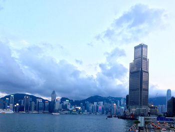 Modern cityscape by sea against sky