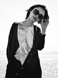 Full length of young woman wearing sunglasses standing against sky