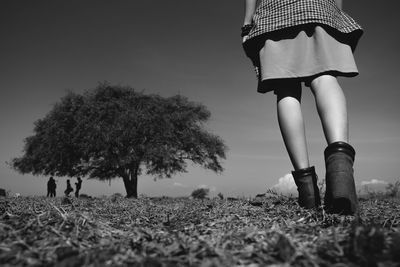 Low section of woman on field against sky