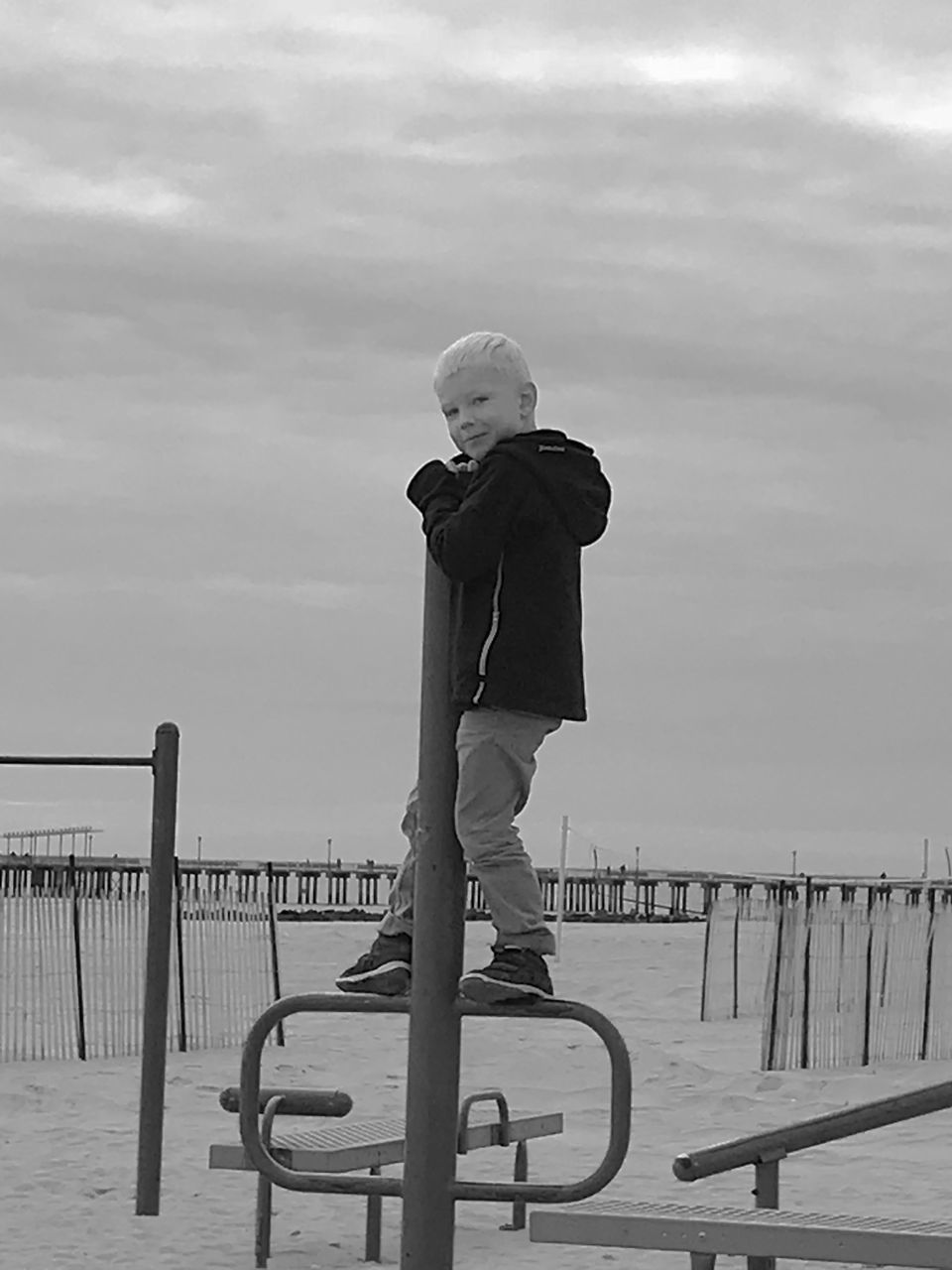 FULL LENGTH OF BOY STANDING ON RAILING AGAINST SEA