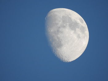 Low angle view of moon against clear blue sky