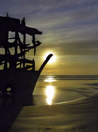 Silhouette people on beach against sky during sunset