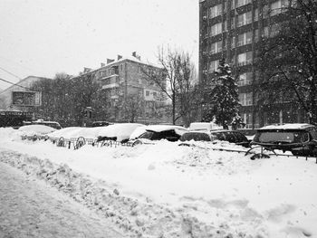 Cars on snow covered city against sky