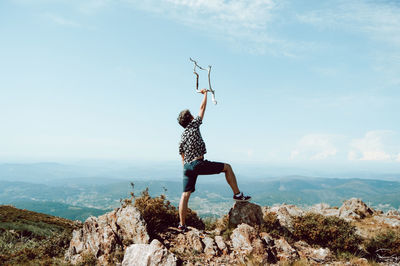 Man standing on rock against sky