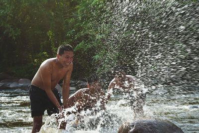 Shirtless men splashing water in lake