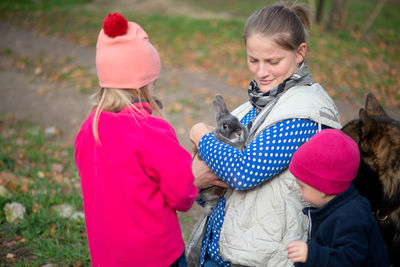 High angle view of mother carrying rabbit while standing with children in park