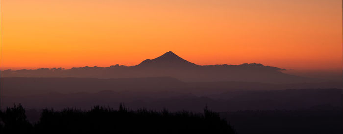 Scenic view of silhouette mountains against romantic sky at sunset