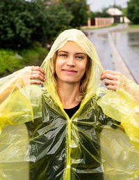 Portrait of smiling young woman wearing raincoat