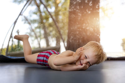 Rear view of boy lying on plant against trees