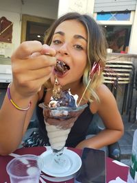 Portrait of woman holding ice cream in restaurant