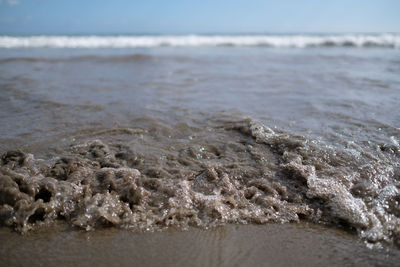 Close-up of wave on beach against sky