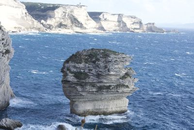 Rock formation in sea against sky