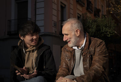 Asian teenage boy and caucasian adult man chatting on street. madrid. spain