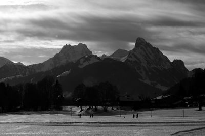 People on snowy field against mountains