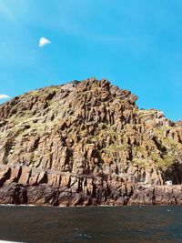 Scenic view of rocks by sea against clear sky