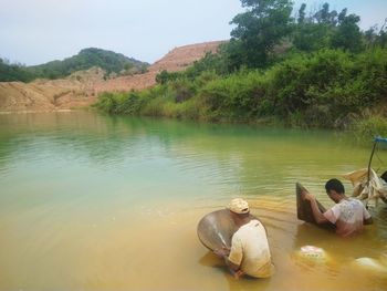 People by lake against mountains