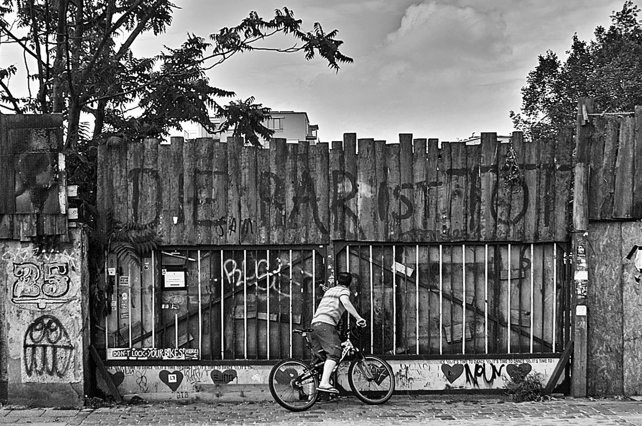 bicycle, building exterior, transportation, mode of transport, architecture, land vehicle, built structure, full length, riding, lifestyles, side view, leisure activity, stationary, men, parked, casual clothing, day, cycling