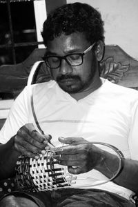 Midsection of man holding eyeglasses while sitting at home