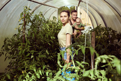 Portrait of young woman standing amidst plants