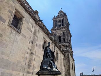 Low angle view of statue against historic building against sky