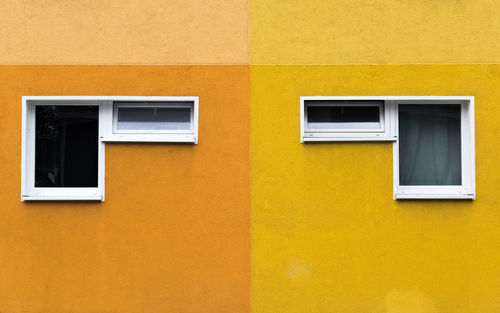 A pair of two windows on yellow and orange facade