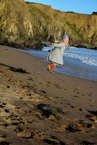 Full length of young woman jumping on beach