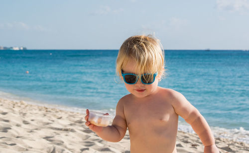 Portrait of shirtless boy at beach against sky