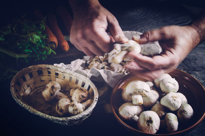 Cropped image of chef peeling mushroom on table