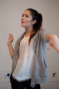 Smiling teenage girl dancing against wall