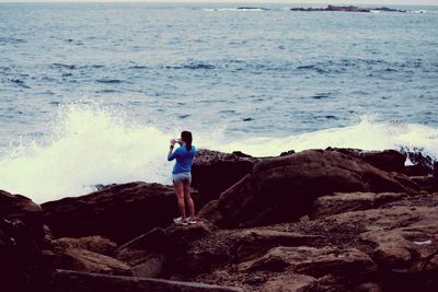Woman standing on rocks at seaside