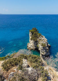 Rocks on shore by sea against sky