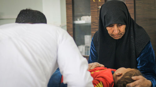 Mother sitting by son while doctor examining